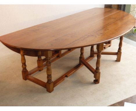 An 18th Century style large and very impressive oval topped cherry wood Harvest Table, the double gate leg action legs with b