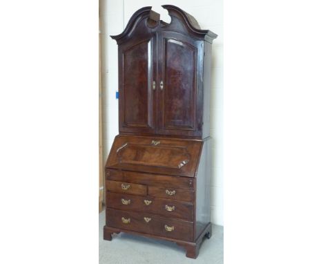 An antique mahogany Bureau Cabinet, the arching swan neck pediment above two highly figures arched panelled doors opening to 