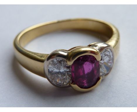 An 18 carat yellow gold Dress Ring, the central hand cut ruby of approx. 0.30 carats and flanked  by two further diamond with