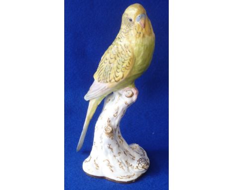 A Royal Worcester porcelain Model of a green and yellow Budgerigar perched on a tree stump, decorated in polychrome with gilt