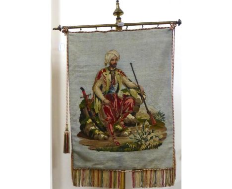A Victorian Needlepoint Panel, in petit point and gros point, depicting a seated Ottoman boy in traditional costume, on a tri