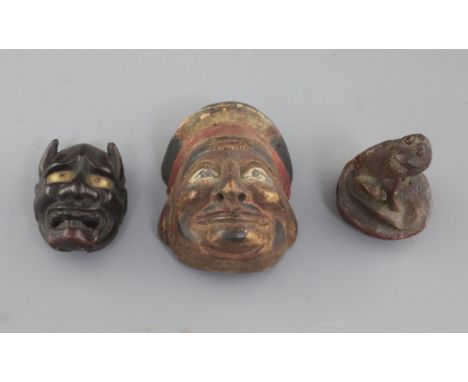 A Japanese bamboo seal in the form of a dog and two wood masks, 19th/20th century, the larger mask of a God of Wealth and the