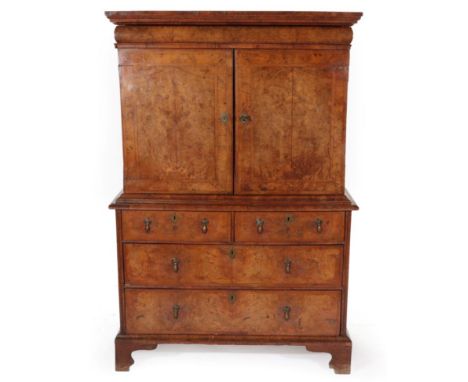  ~ A George I Figured Walnut and Feather-Banded Cabinet on Stand, early 18th century, with cushion shaped drawer above cupboa
