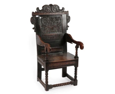 A 17th Century Joined Oak Wainscot Armchair, dated and initialled 1605 AID, the scrolled top rail above a parquetry decorated