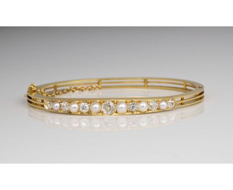 A fine Victorian 18ct yellow gold, pearl and diamond bangle, the hinged bangle with foliate engraved decoration, set with alt