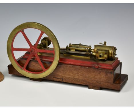 A well engineered stationary horizontal single cylinder live steam engine, single spoked flywheel to side, painted red, stand