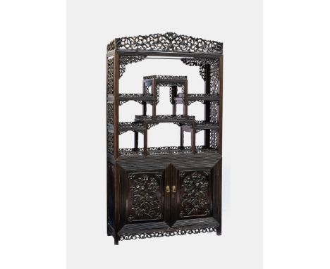 A Chinese carved and ebonised hardwood two part display stand cabinet, early 20th century, with reeded borders and foliate ca