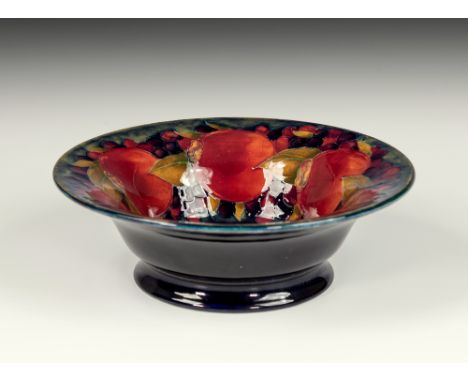 An early William Moorcroft Pomegranate bowl, c1918, the circular bowl on a short, waisted foot, painted on a dark blue ground