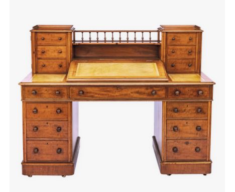 A late-Victorian faded mahogany Dickens desk, the top with two banks of three graduated drawers united by a single shelf and 