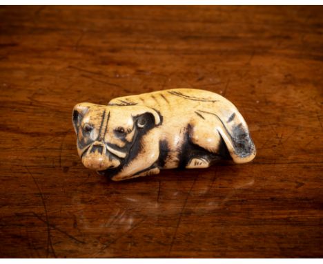 A Japanese carved bone netsuke of a recumbent water buffalo, 18th / early 19th century, with inset amber eyes, signed to base