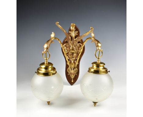 A Victorian style gilt brass twin branch wall light, the foliate cartouche form plate on a wooden mount, suspending two barle