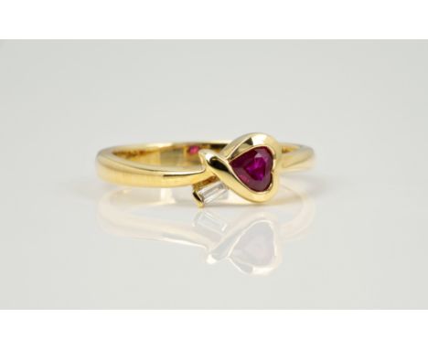 An 18ct yellow gold, ruby and diamond heart ring, the heart cut ruby in a cross over setting set with a single baguette cut d