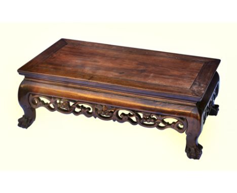 A 19th century Chinese carved hardwood low opium table, the cleated top over a convex frieze and pierced fruit and foliate sc