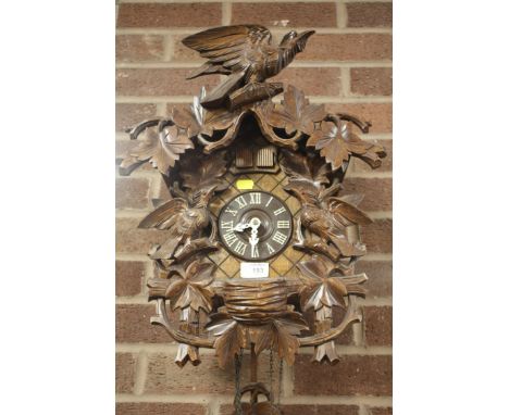 A CARVED BLACK FOREST STYLE CUCKOO CLOCK WITH WEIGHTS AND PENDULUM 