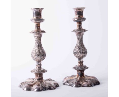 Pair of Georgian style silver plated candlesticks with heavily embossed scroll columns on padded scroll bases, dimensions 25.