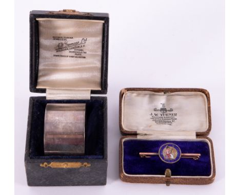 A 9ct bar brooch surmounted with an enamelled four pence, 1846, also a George V silver cased napkin ring (2).