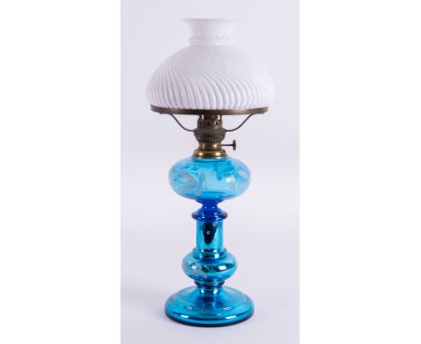 A blue glass oil lamp decorated with white flowers with a white shade, height 49cm.