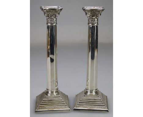 Rosenzweig, Taitelbaum and Co, a pair of hollow cast Corinthian column form silver table candlesticks, each with beaded detac