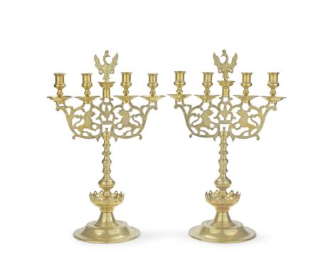 A PAIR OF CONTINENTAL BRASS FOUR-LIGHT CANDELABRAEach with four turned sconces and drip pans, centred with a phoenix above a 