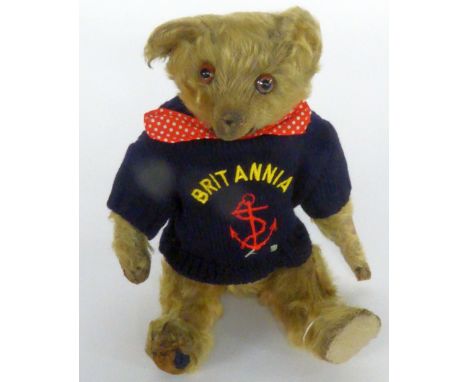 AN EARLY 20TH CENTURY STEIFF TYPE GOLDEN PLUSH TEDDY BEAR with distressed and replaced felt pads, hump back and protruding mu