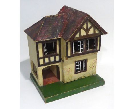 SMALL 20th CENTURY PAINTED WOODEN AND METAL DOLLS HOUSE WITH GARAGE, printed paper simulated tile roof, on a green plinth bas