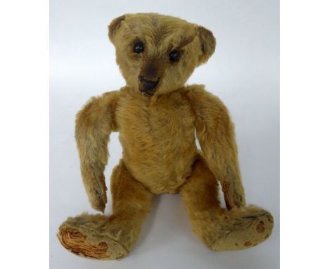 A SMALL CIRCA 1910 GERMAN STEIFF GOLDEN PLUSH TEDDY BEAR, the felt pads in poor condition, hump back, long arms and protrudin