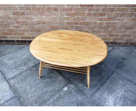 AN ERCOL LIGHT ELM OCCASIONAL TABLE  the oval top 100cm x 83cm, on beech supports with rack underframe, 45cm high