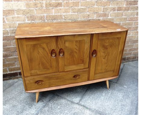 A SMALL ERCOL LIGHT ELM SIDEBOARD  with cupboard above drawer beside further cupboard, 114cm wide 49cm deep 83cm high