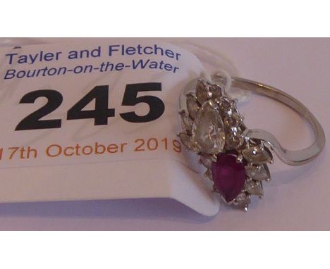 A ladies white-metal dress ring mounted with a pear-shaped ruby and pear-shaped diamond surrounded by further smaller diamond