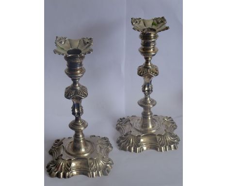 A pair of late George II period mid-18th century hallmarked silver cast candlesticks in rococo style, each with detachable dr