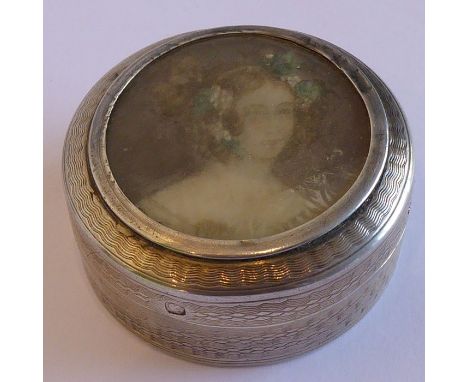 A 19th century French silver circular box and cover, the lid with a shoulder-length portrait miniature of a young lady above 