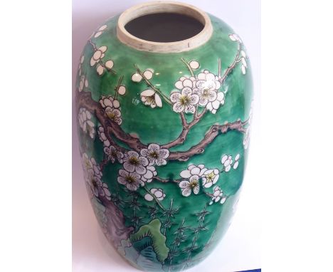 An early 20th century Japanese pottery vase decorated with birds amongst prunus blossom against a green ground (minus cover) 