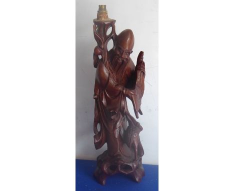 An early 20th century Chinese hardwood carving of an immortal holding a scroll and with a stork at his feet, (now as a lamp) 
