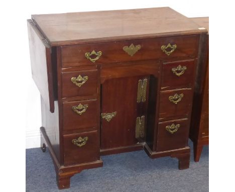 A mid- to late 18th century mahogany kneehole desk; the two drop-leaves flanking an arrangement of single full-width top draw