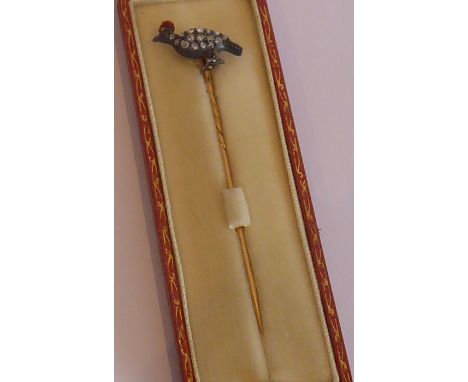 A leather-cased stick pin, rose-gold-coloured pin (marked) and the finial with a white-metal bird crested with red enamel and