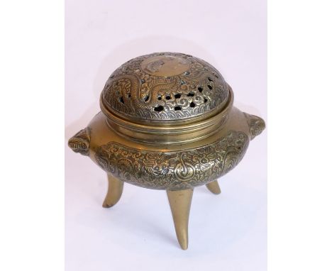 A Chinese brass tripod censer the two handles modelled as mythical beast heads and the pierced cover engraved and decorated w