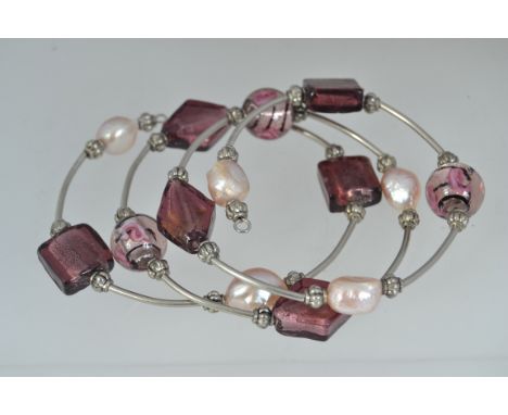 A baroque pearl and foil lined amethyst glass bead coil bangle bracelet with white metal beads.