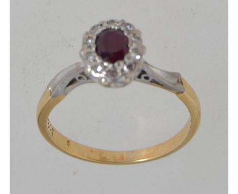 An 18ct gold  ring set with a central oval cut ruby surrounded by a halo of diamonds. Size J. Tests 18ct gold. Marked 18ct.