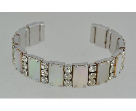 A vintage white metal and mother of pearl cuff bracelet bangle with intermittent rhinestones and mother of pearl.
