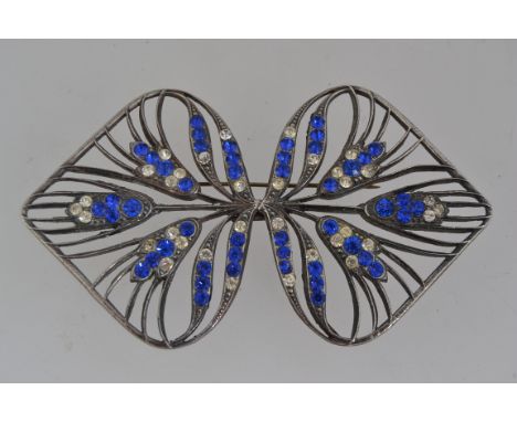 A large 1920s Art Nouveau white metal brooch with blue and clear paste stone decoration in a pierced stylized peacock feather