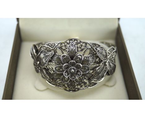 An ornate white metal filigree bangle, modelled as a flower, 33.2g