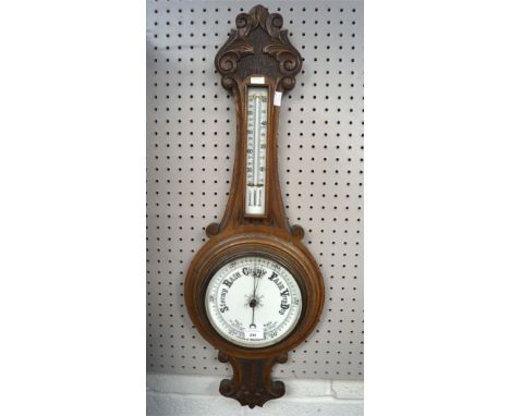 A carved oak wall aneroid barometer and thermometer, with carved scrolling decoration, 87cm high