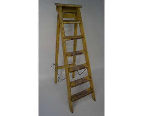 A vintage yellow painted set of step ladders, approximately 154cm high