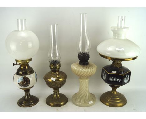 Four 19th/20th century oil lamps with glass, brass and ceramic reserves, one decorated with landscape roundels, the other wit