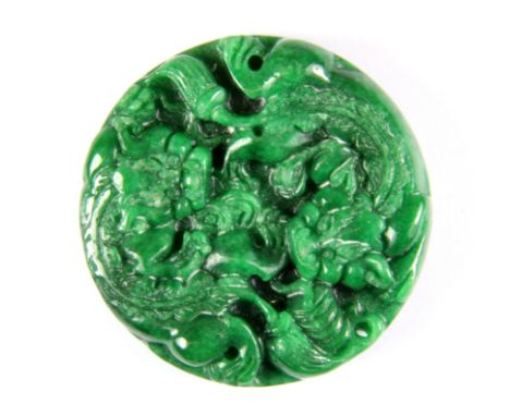 A Chinese carved apple green jade amulet featuring two lion dogs on the front and lotus, bat and coins on the reverse, Dia. 5