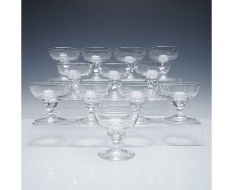 A set of twelve elegant Steuben champagne coupes, each finely crafted in brilliant clear crystal and featuring the brand's si