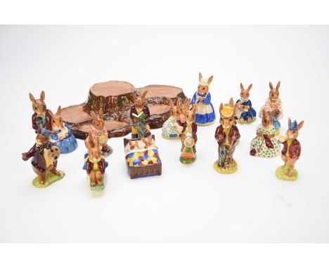 A collection of fifteen Royal Doulton 'Bunnykins' figures together with a Beswick tree trunk plinth stand, the figures includ