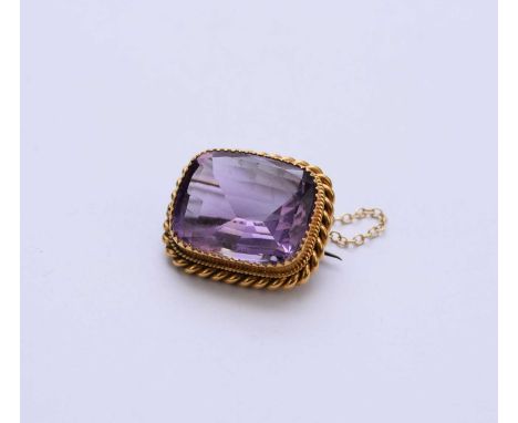 An amethyst set brooch, designed as a large single cushion cut amethyst measuring approx 19 x 15mm, claw set in yellow metal 