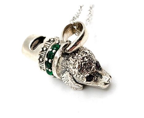 A silver dog's head whistle with green glass collar and ruby eyes, on a 46cm silver chain, 10.0gms.