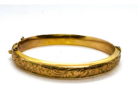 A 9ct yellow gold hollow hinged bangle with foliate top design. 9.5gms.